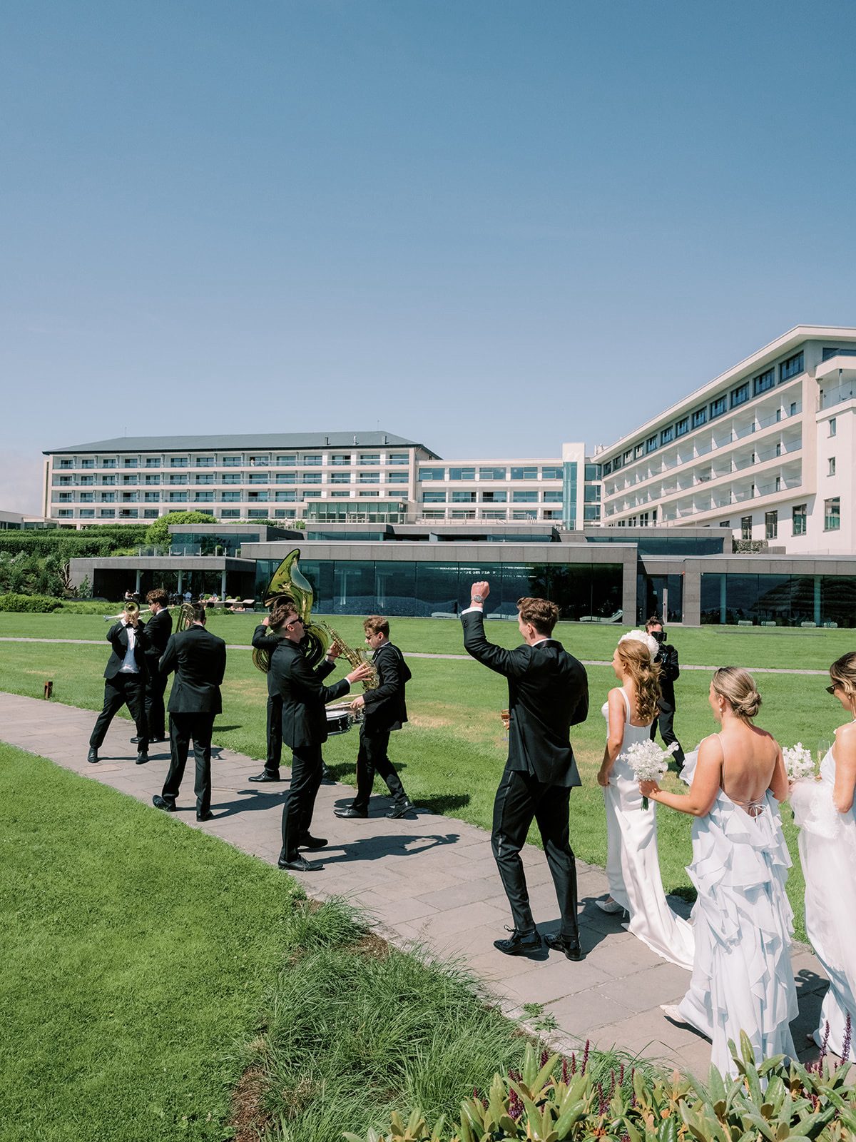 Wedding party cheering as Brasswork leads across the lawn